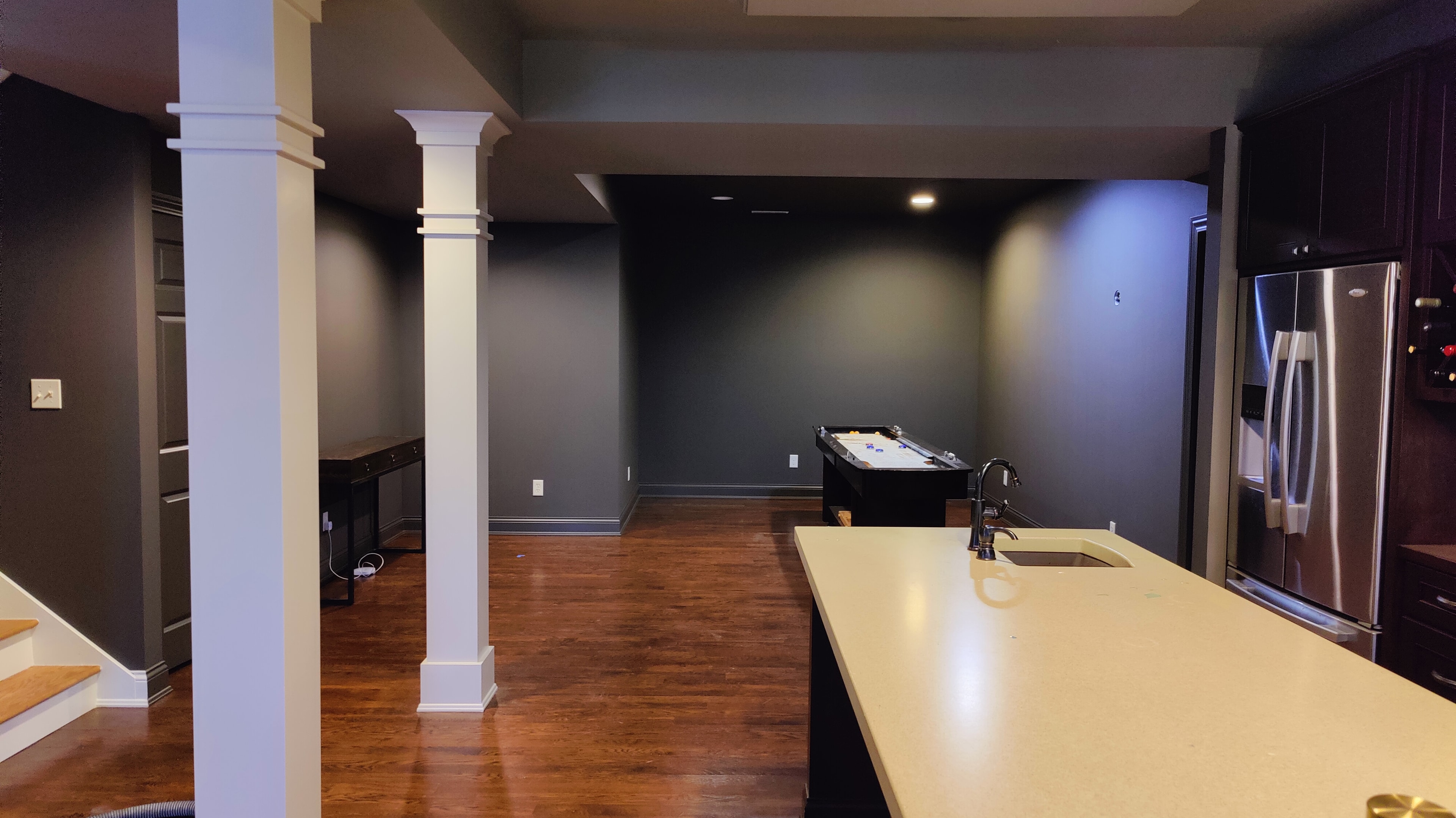 Finished basement with deep charcoal walls, white columns, and painted trim — Grand Rapids area