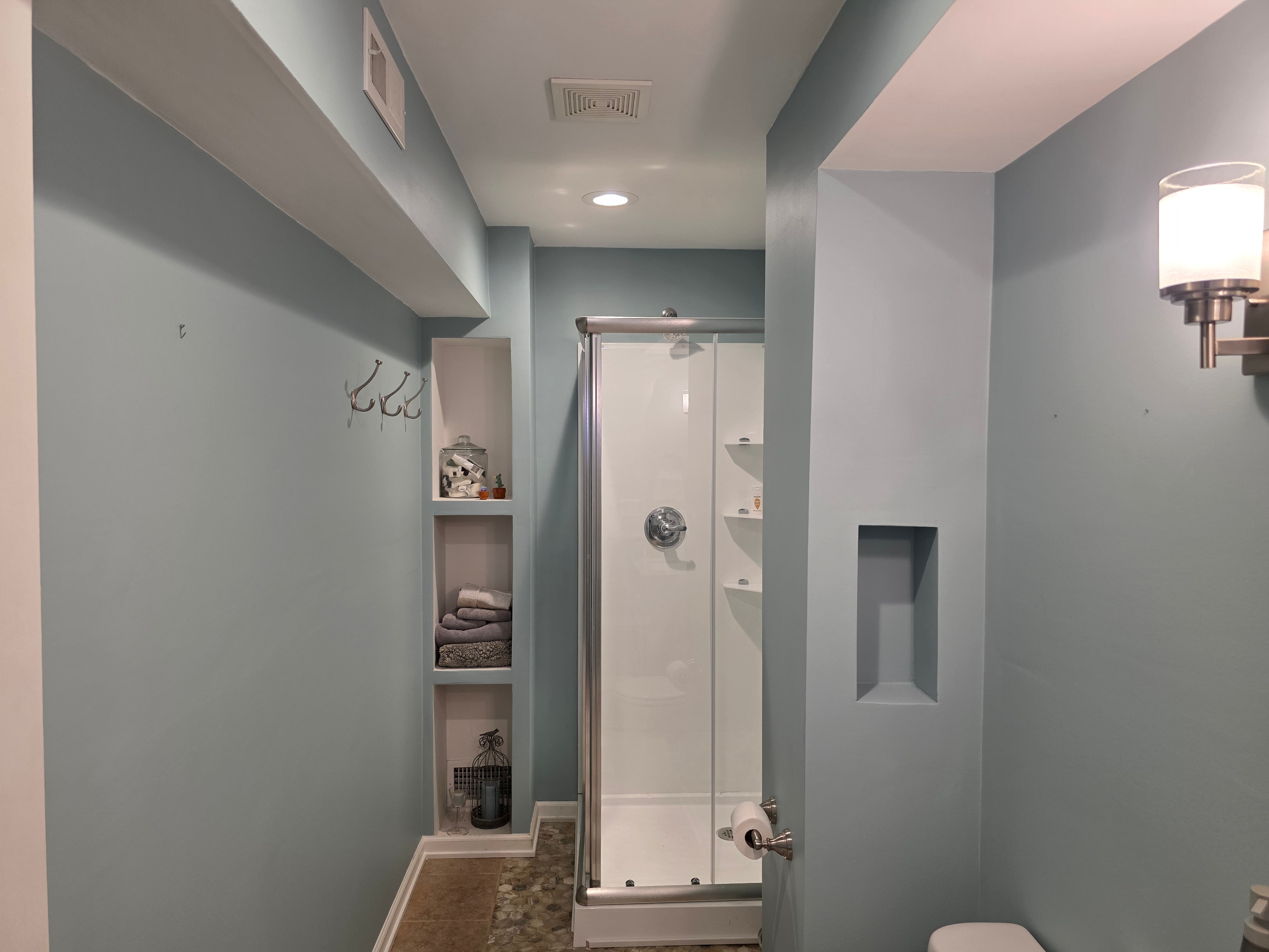 Basement bathroom with soft blue-gray walls, built-in shelving, and crisp white trim — Caledonia, MI